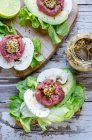 Open sandwiches with beef tartar, mustard, mushrooms, avocado and lettuce — Stock Photo