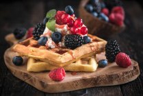 Belgian waffles with ice cream and berries on a wooden board — Stock Photo