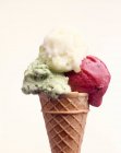 Un cono con tres cucharadas de helado con sabor diferente - foto de stock