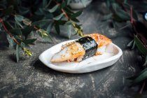 Sushi nigiri com enguia e sementes de gergelim em mini prato — Fotografia de Stock