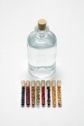 Ginebra en una botella con varios aromas en tubos de ensayo - foto de stock