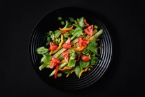 Insalata con verdure fresche e rucola su fondo nero — Foto stock