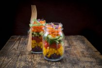 Rainbow salad in glass jars with red cabbage, yellow pepper, tomato, cucumber, carrots and beetroot sprouts — Stock Photo