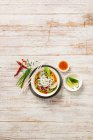 Blick von oben auf thailändisches Essen mit Gemüse und Soße auf Holzgrund — Stockfoto