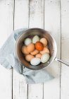 Ovos brancos e marrons em panela de metal com pano azul — Fotografia de Stock