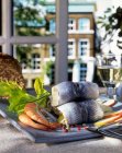 Роликовые швабры и креветки на тарелке перед окном — стоковое фото