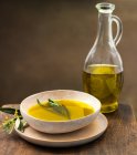 Azeite de oliva em uma tigela com ervas e especiarias em um fundo escuro. — Fotografia de Stock