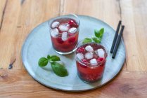 Glasses of drink with basil seeds, leaves and raspberries — Stock Photo