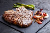 Смажений яловичий стейк з гарніром, подається на тарілці з шиферу — стокове фото