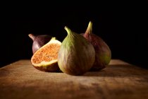 Fresh figs, whole and halved, on a wooden table — Stock Photo
