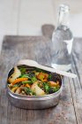 Lentilles et riz aux champignons, carottes et brocoli dans une boîte à lunch devant une bouteille d'eau — Photo de stock