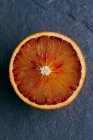 Половина кровавого апельсина на сером фоне — стоковое фото