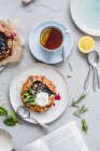 Blueberry galettes with almonds, herbs and vanilla cream served with a cup of tea — Stock Photo