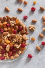 Nüsse und Trockenfrüchte auf dem Teller auf der Betonoberfläche — Stockfoto