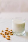Стакан молока и миндаля на белой скатерти — стоковое фото