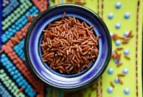 Red rice in a bowl on a colourful background (seen from above) — Stock Photo