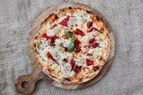 A cheese pizza with bresaola and basil — Stock Photo