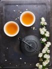 Tea bowls, teapot and white flowers — Stock Photo
