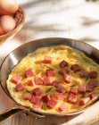 Omelette with ham cubes in a pan — Stock Photo
