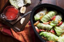 Фаршированная капуста в сковороде с яблочными ломтиками, расинами и томатным соусом — стоковое фото