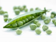 A pea pod surrounded by peas — Stock Photo