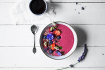 A smoothie bowl with fruits, edible flowers and gluten-free muesli — Stock Photo