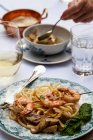 Відкритий стіл з макаронними виробами cacio e pepe (паста з сиром та перцем), креветками-шампурами з базиліком, артишоками та білим вином — стокове фото
