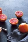 Naranjas de sangre, enteras y cortadas a la mitad, sobre una superficie gris de hormigón - foto de stock