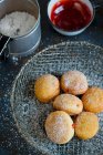Donuts in einem Drahtkorb, eine Tasse Marmelade und eine Dose Puderzucker — Stockfoto