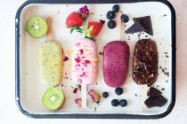 Kiwi, strawberry, blueberry and chocolate popsicles — Stock Photo