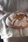 A fresh loaf of crusty bread on a linen cloth — Stock Photo
