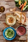 Red, green and yellow hummus in bowls with flatbread — Stock Photo