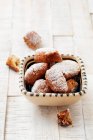 A bowl of homemade, deep-fried pastries with icing sugar — Stock Photo
