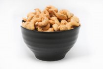 Roasted and salted cashews in a black bowl — Stock Photo