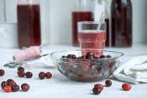 Cherries in glass bowl and on white table surface — Stock Photo