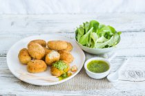 Breaded fishcakes with green sauce and salad — Stock Photo