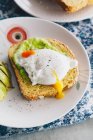 Oat and sweet potato bread topped with avocado and poached egg — Stock Photo
