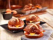 Panecillos de lejía con tocino, queso y huevo frito - foto de stock