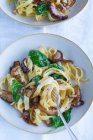 Феттучини со шпинатом, грибами и карамелизированным луком — стоковое фото