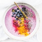 A smoothie bowl with berries, turmeric, chia seeds, black sesame seeds and lavender — Stock Photo