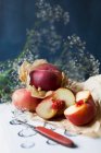 Frische Pfirsiche, ganz oder halbiert, auf braunem Papier — Stockfoto