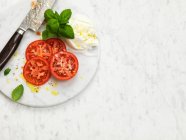 Свіжий салат з помідорами, моцарелою, базиліком та сиром . — стокове фото