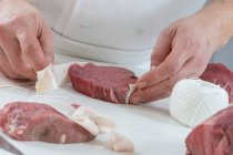 Un chef enveloppant un steak de filet dans du bacon — Photo de stock