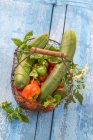 Tomates, pepinos e ervas em uma cesta de arame — Fotografia de Stock