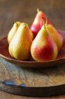 Yellow and red pears on a wooden plate — Stock Photo