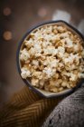 Vanille-Zimt-Popcorn in einer annamelförmigen Pfanne mit Decken vor dunklem Hintergrund mit Lichterketten — Stockfoto