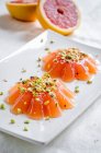 Pink grapefruit jellies with pistachio nuts served on plate — Stock Photo