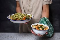A woman holding two bowls of green tagliatelle with seafood — Stock Photo