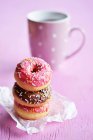 Uma pilha de três mini donuts com gelo e fios de açúcar na frente de uma xícara de chá — Fotografia de Stock
