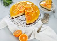 Pastel de queso naranja con una base de chocolate, cubierto con rodajas de naranja y jalea de naranja (vegetariano) - foto de stock